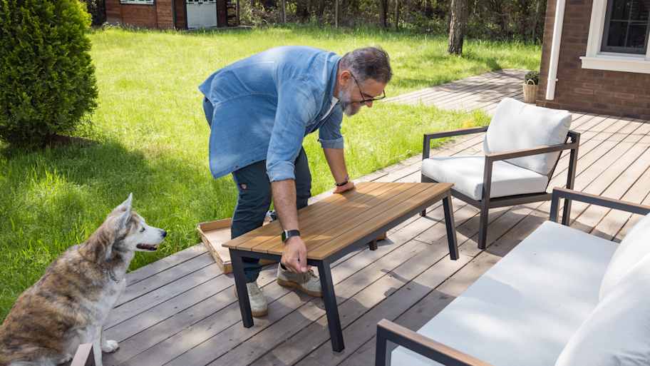 A man placing furniture on the patio